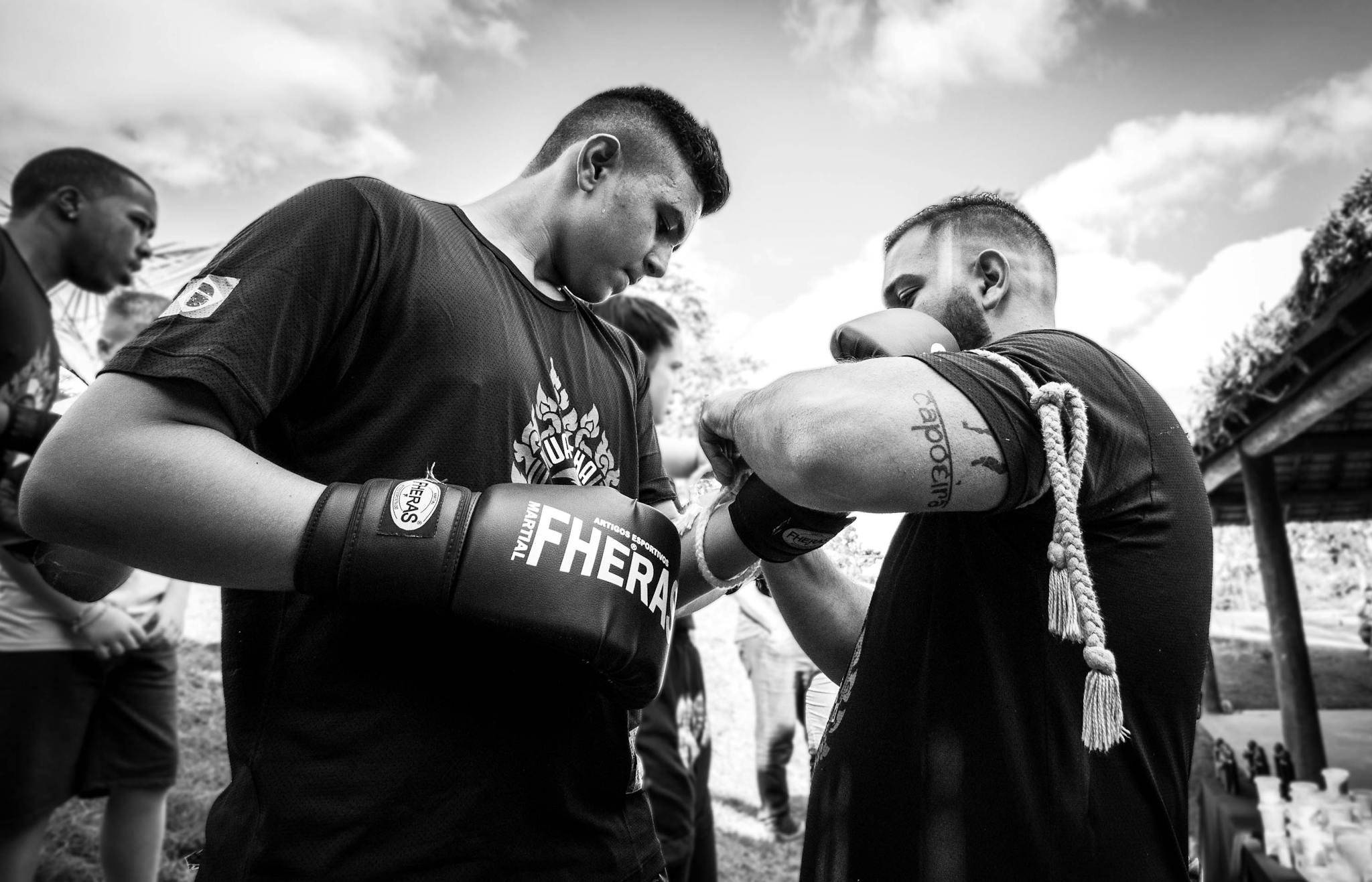 A trainer prepares a young boxer outdoors during a training session, showcasing focus and dedication.