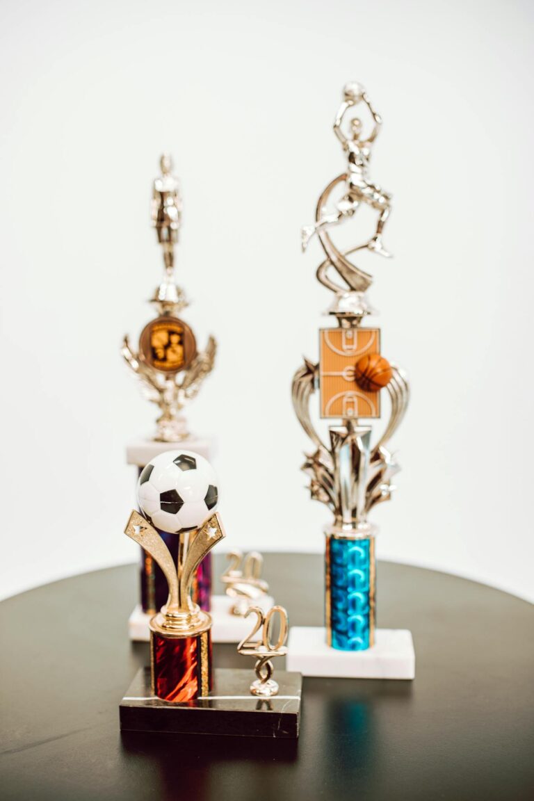 Close-up of various sports trophies featuring basketball and soccer designs on a table.